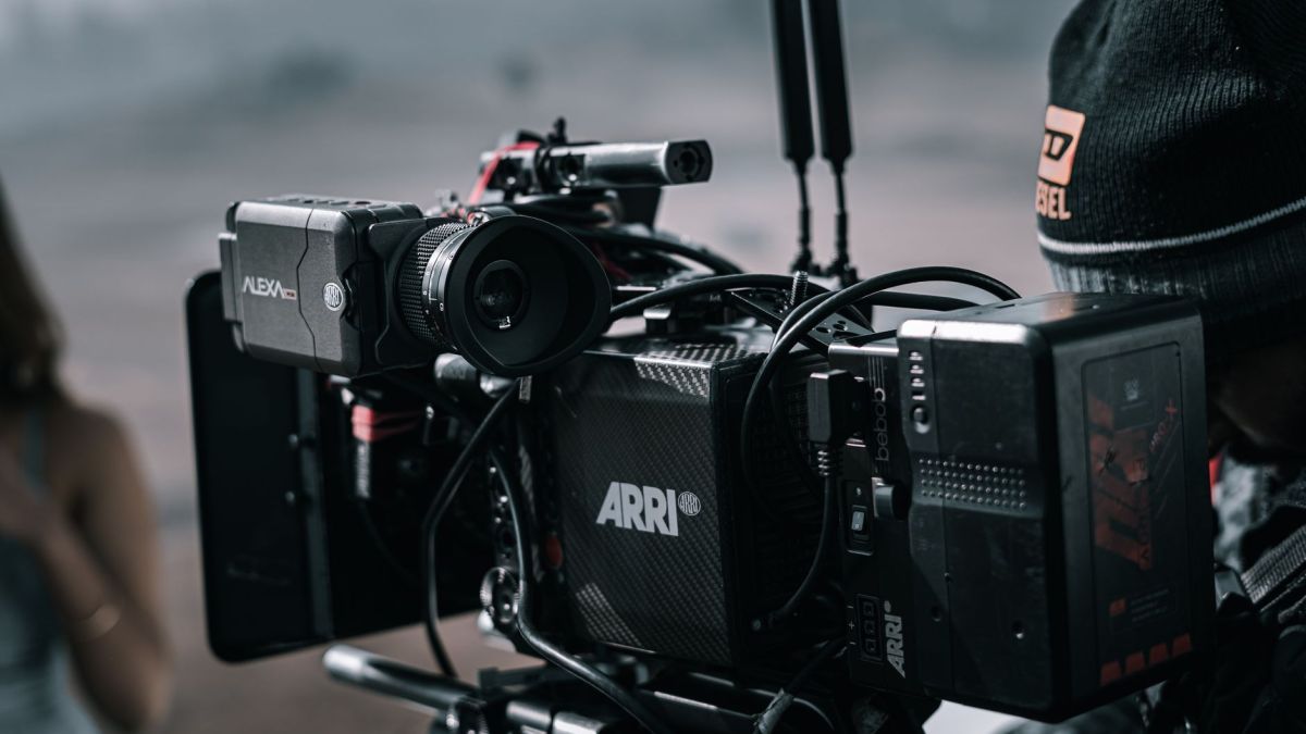 Close-up of a professional filmmaking camera setup on an outdoor set with blurred background.
