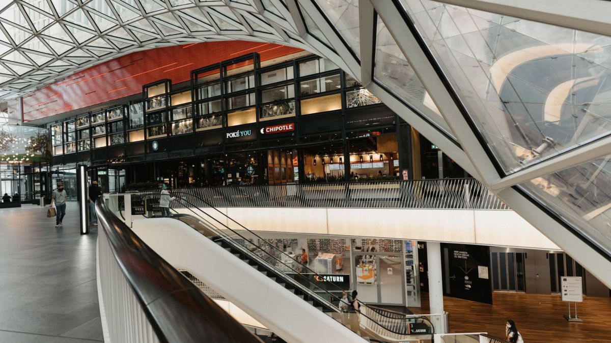 Interior view of a modern shopping mall featuring a striking glass ceiling and multiple floors.