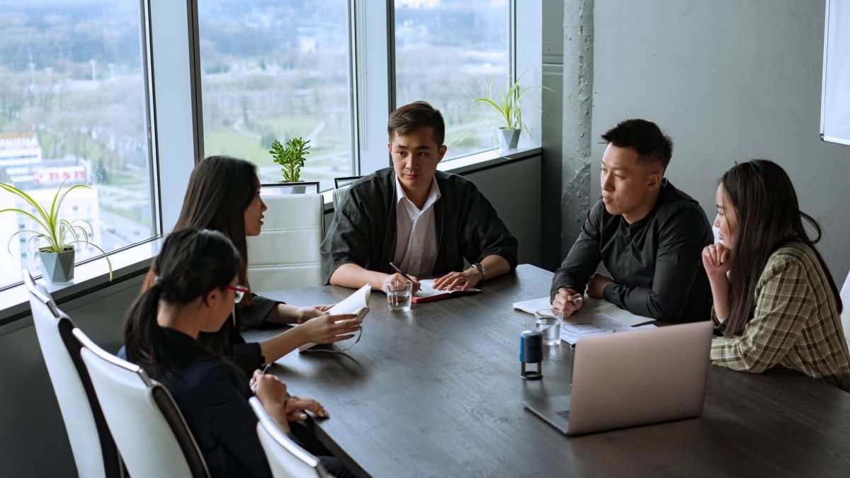 Group of Asian professionals having a meeting in a modern office setting.