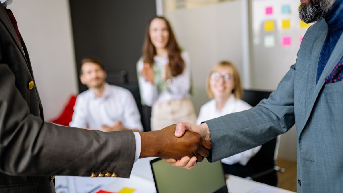 Close-up of a handshake between colleagues in a professional office setting, emphasizing teamwork and agreement.