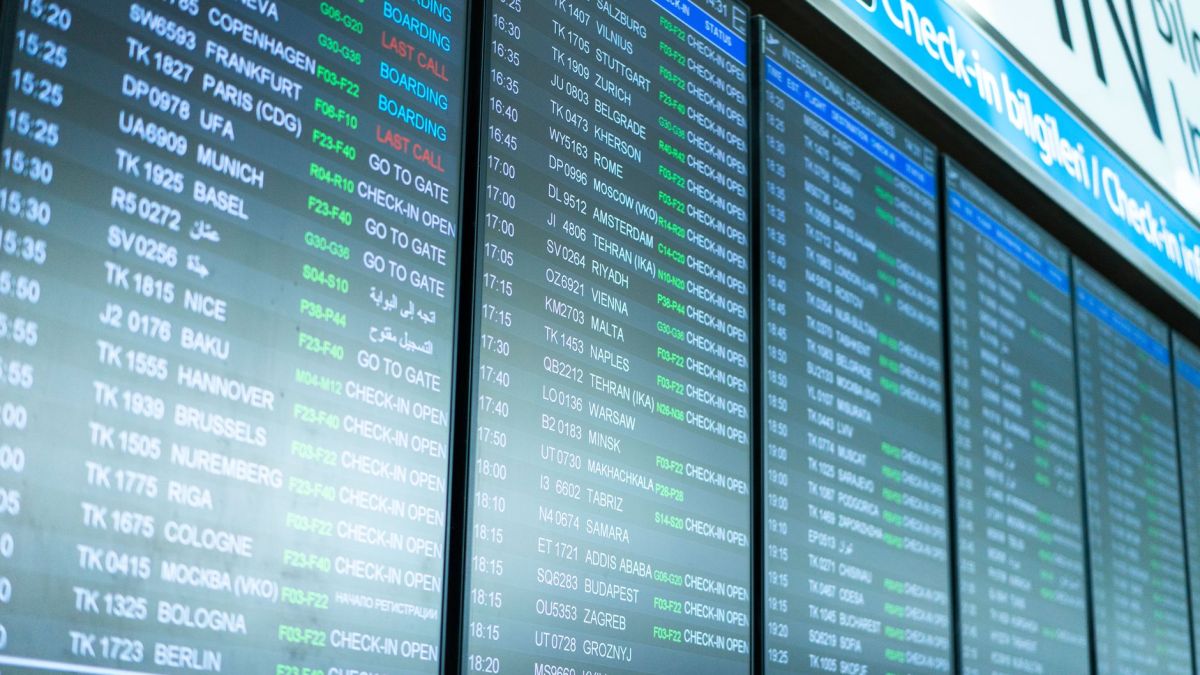 Digital screens display flight information and schedules at an airport terminal.