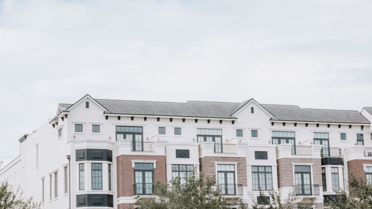 A stylish, multi-story luxury apartment building with a contemporary facade against a clear sky.