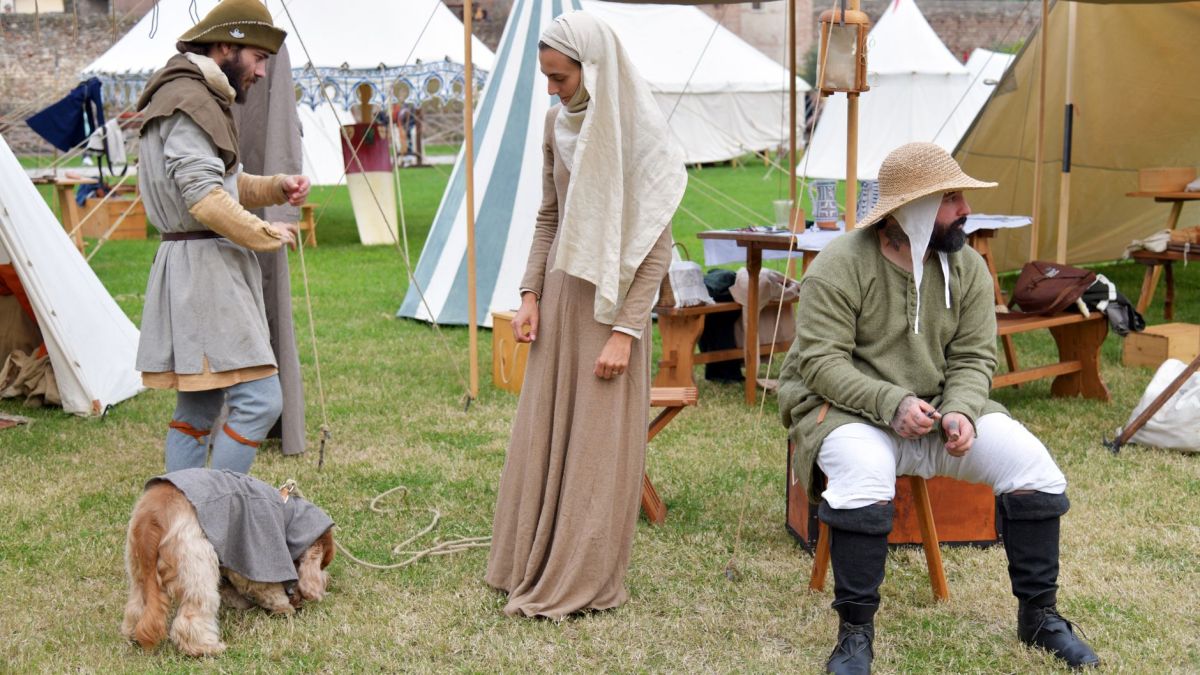 People dressed in medieval attire at a historical reenactment event outdoors.