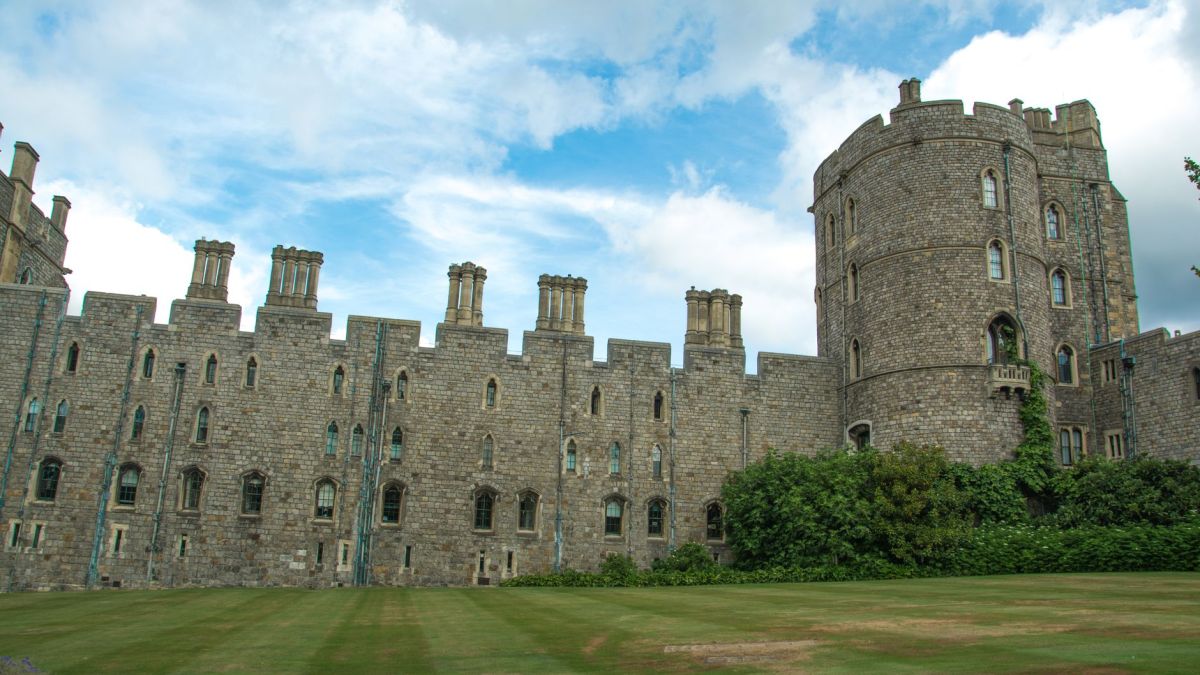 Windsor Castle's historic stone facade under a vibrant blue sky, showcasing its iconic turrets.
