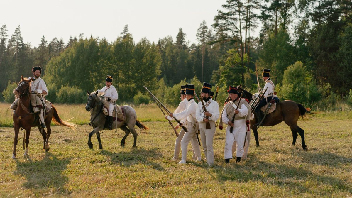 Group of reenactors depicting historical soldiers in uniform with rifles and horses.