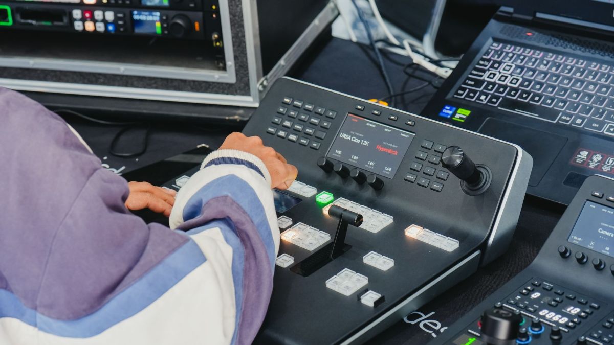 Operator managing video switcher in a professional control room with advanced equipment.