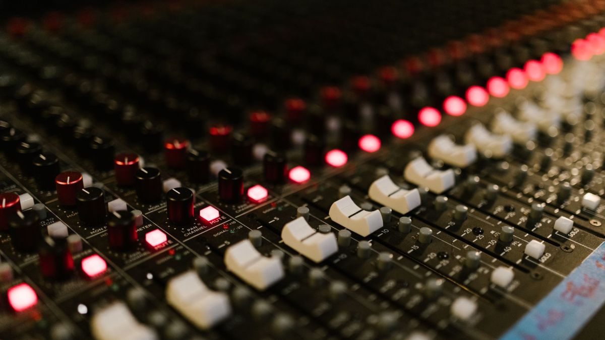 Close-up of a sound mixing console with illuminated control knobs in a music studio.
