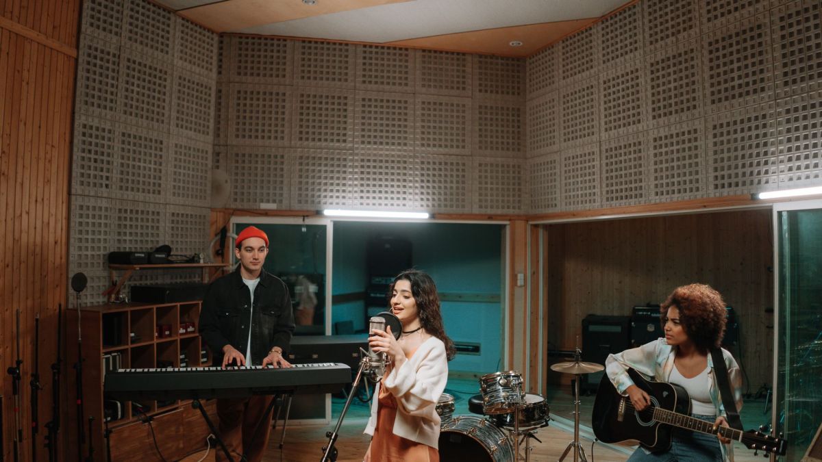 A diverse band practicing music in a professional recording studio setting.