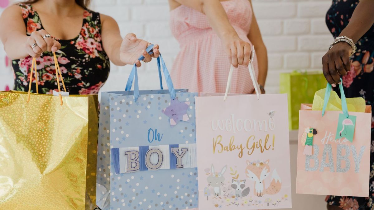 Women holding various colorful baby shower gift bags, perfect for joyful and festive occasions.