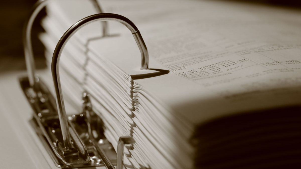 Detailed sepia close-up of a binder filled with documents, emphasizing texture.