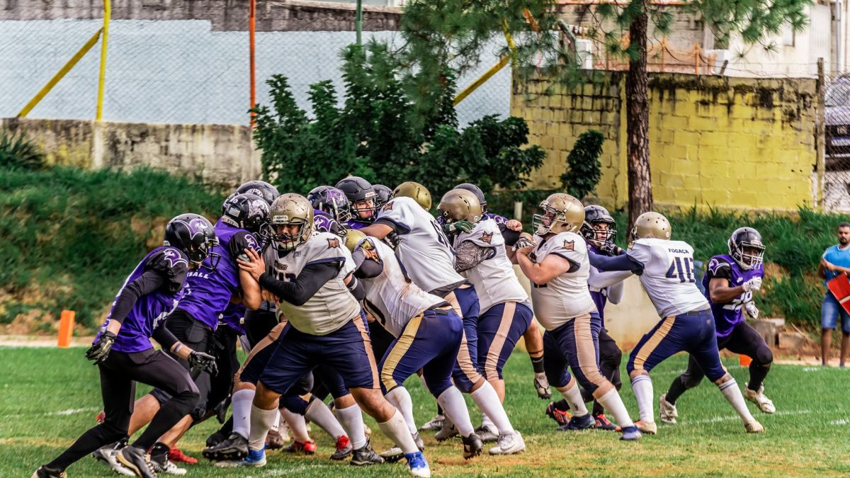 Football players in colorful uniforms compete during a sunny outdoor game.