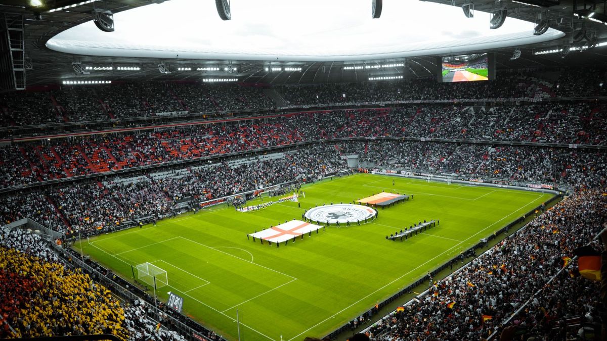 A vibrant soccer stadium filled with fans watching a game, flags displayed on the field.
