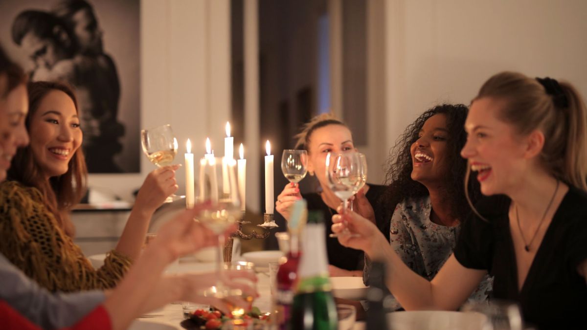 A group of women enjoying a lively dinner party with wine and candlelight, showcasing friendship and happiness.