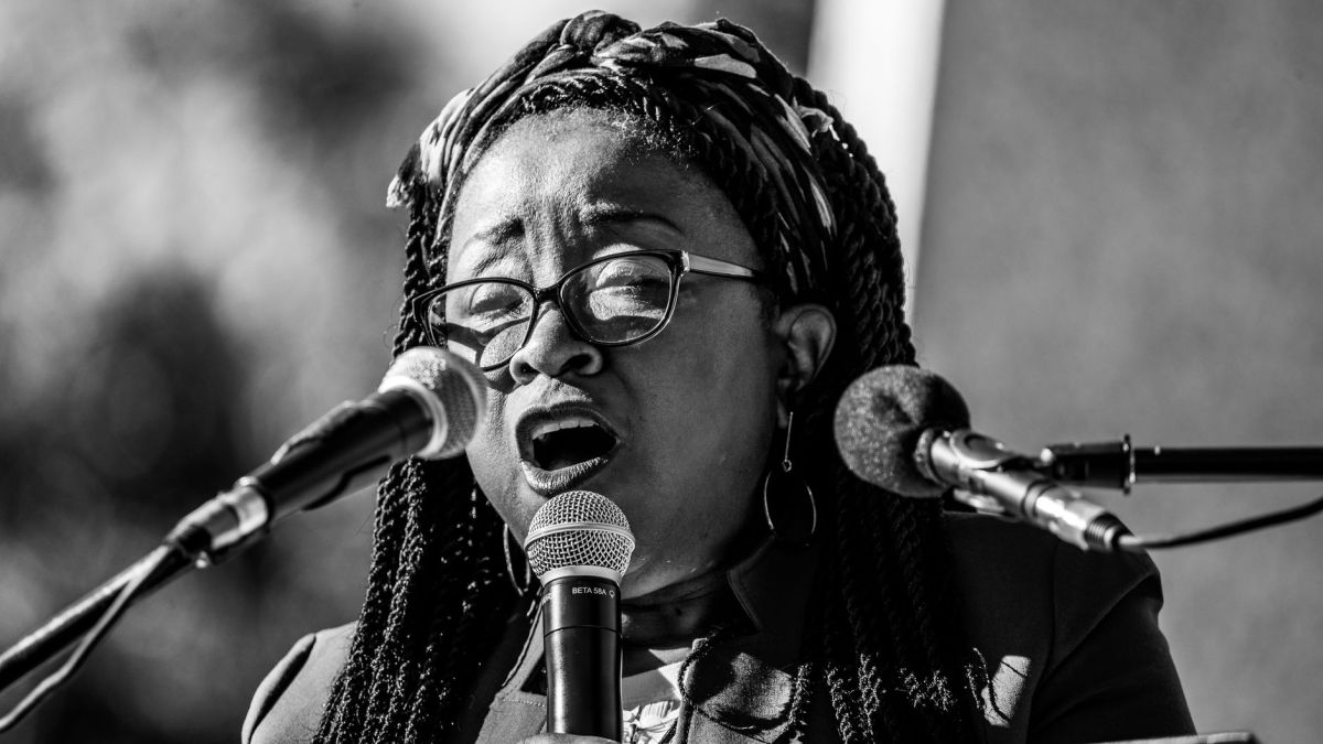 Black and white portrait of an African American woman singing into a microphone, exuding passion and emotion.