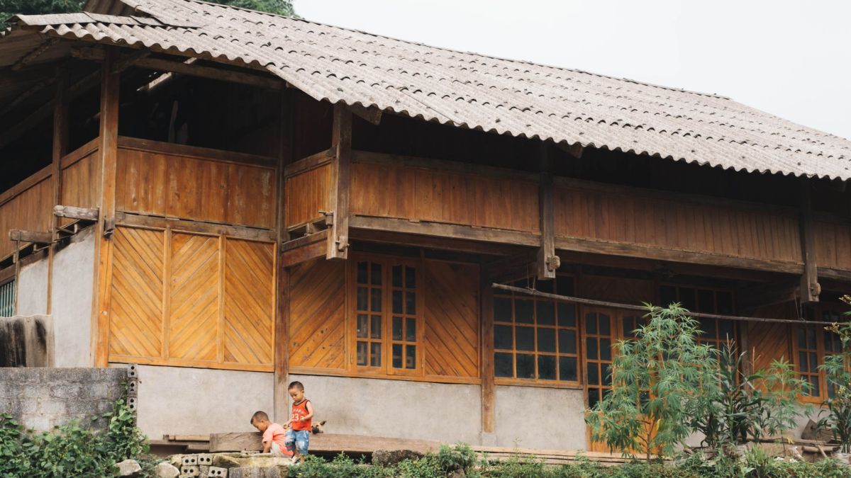 Rural scene of children playing by traditional Vietnamese wooden house in Lào Cai.