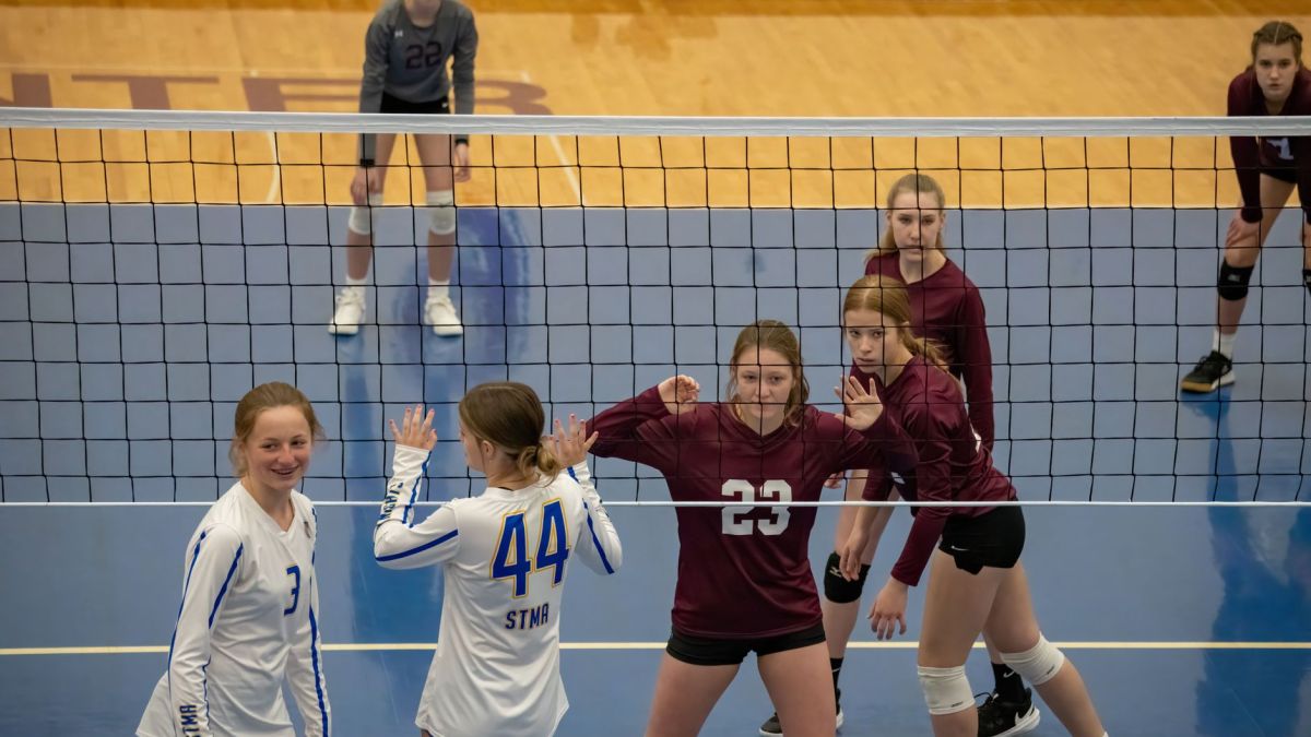 Teen girls playing volleyball indoors in Rochester, MN, showcasing teamwork and competition.