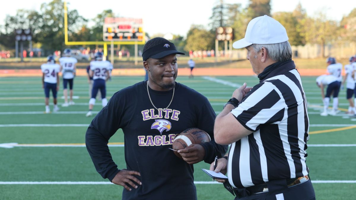 A referee and a football coach discuss the game strategy on the field.