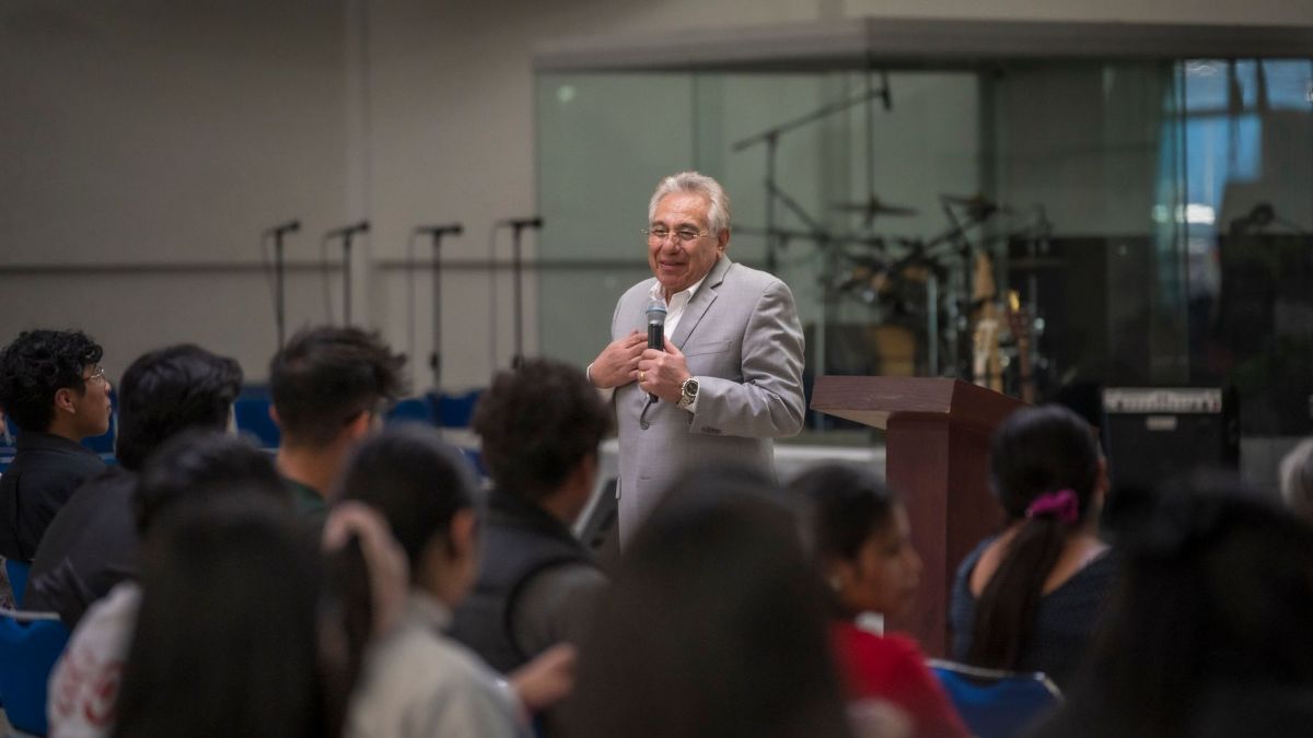 Speaker delivers engaging lecture in university hall to attentive audience with musical equipment in background.
