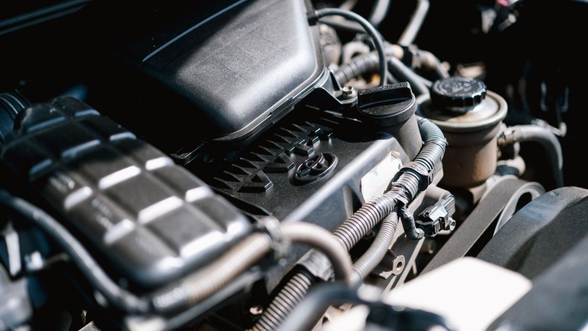 Detailed view of car engine parts, showcasing cables and components with bright lighting.