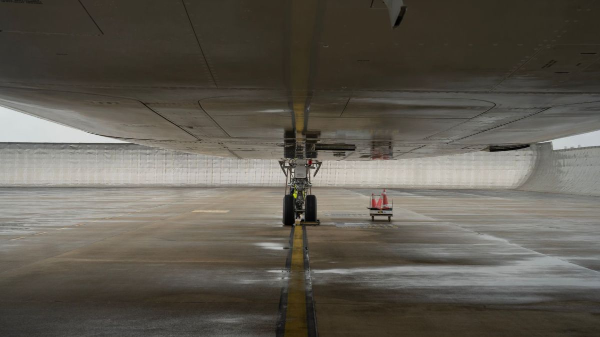 Close-up view of aircraft undercarriage on a wet airport tarmac, highlighting engineering details.