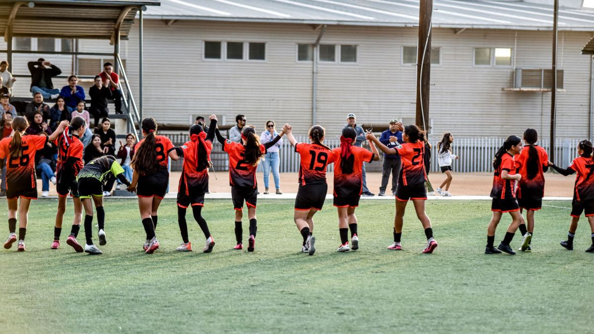 Women's soccer team celebrates victory with fans in stadium.