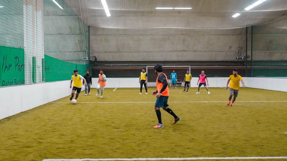 A lively indoor soccer game with diverse players actively engaging in the sport.