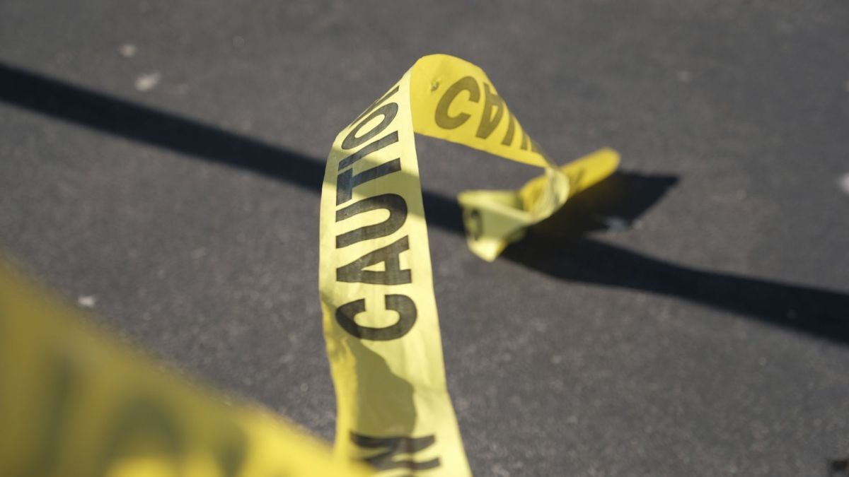 Close-up of yellow caution tape on pavement, suggesting danger or warning.