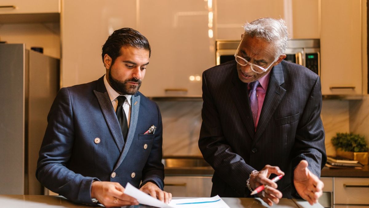 Two businessmen engaged in a focused discussion over financial documents in a modern office setting.
