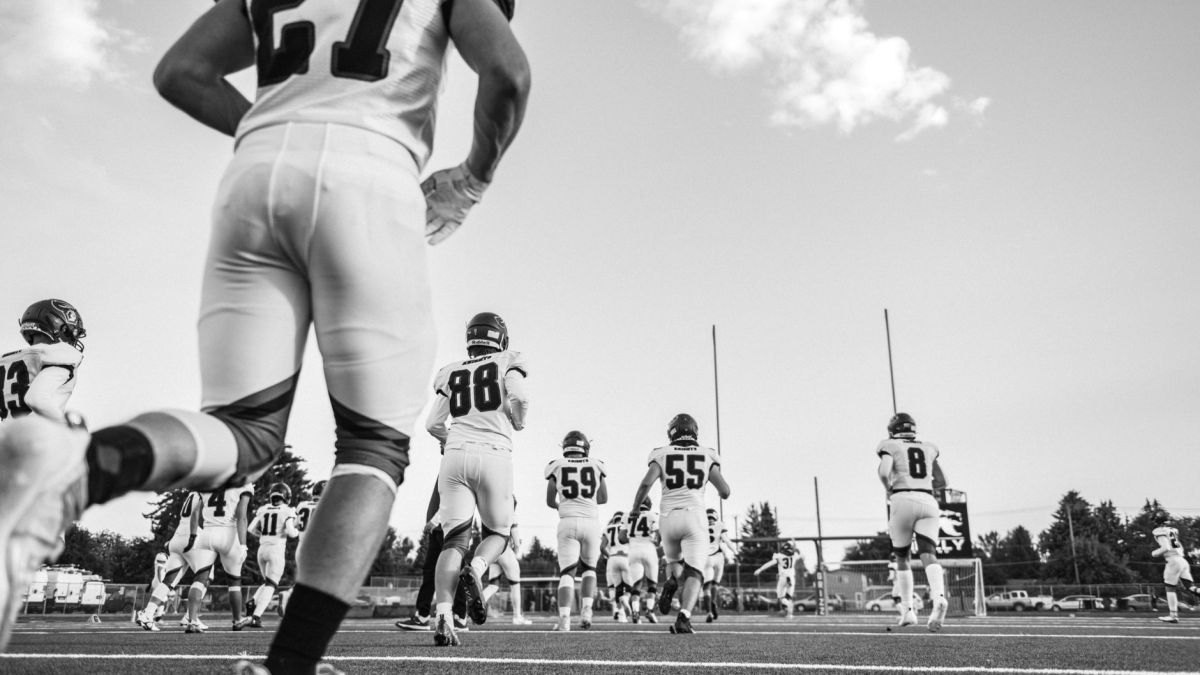 Dramatic black and white photo capturing high school football players in action on the field.
