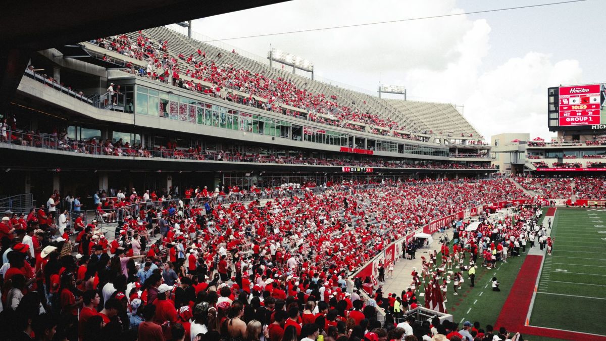 A vibrant crowd in a stadium cheering during an outdoor football game, creating an energetic atmosphere.