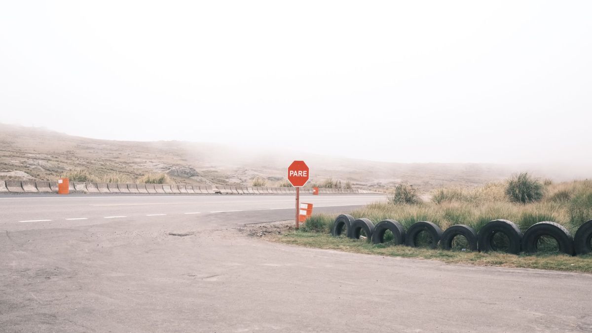 Empty foggy road with a stop sign and tires, creating a moody summer scene.