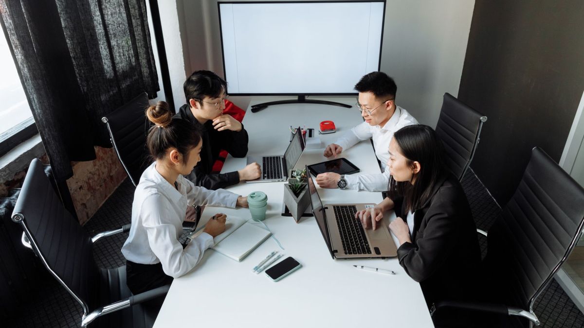 Four professionals collaborating over laptops in a bright, modern office space.