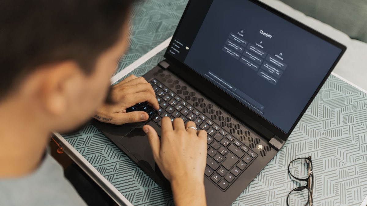 A man working on a laptop with AI software open on the screen, wearing eyeglasses.