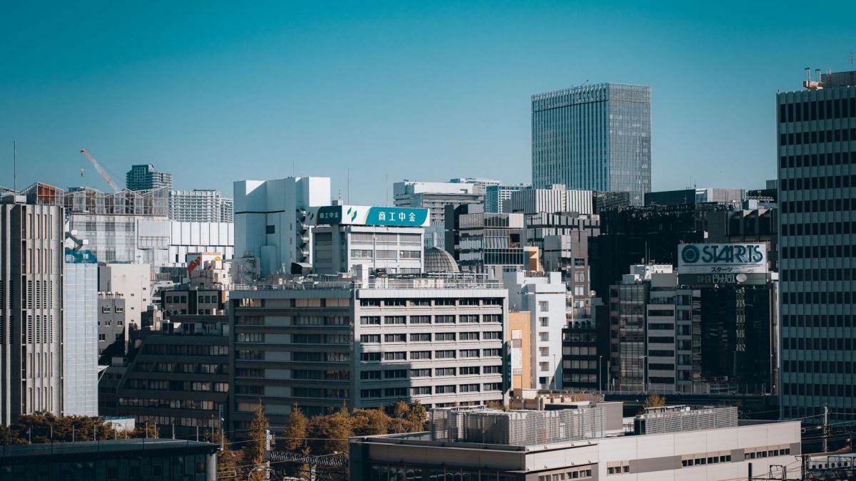 Aerial view of Tokyo's modern skyline features towering buildings and urban architecture under a clear blue sky.