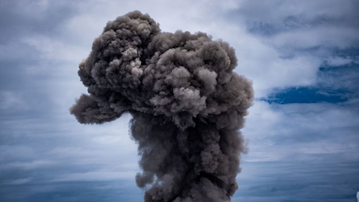 A spectacular display of volcanic ash rising into a cloudy sky, illustrating natural power.
