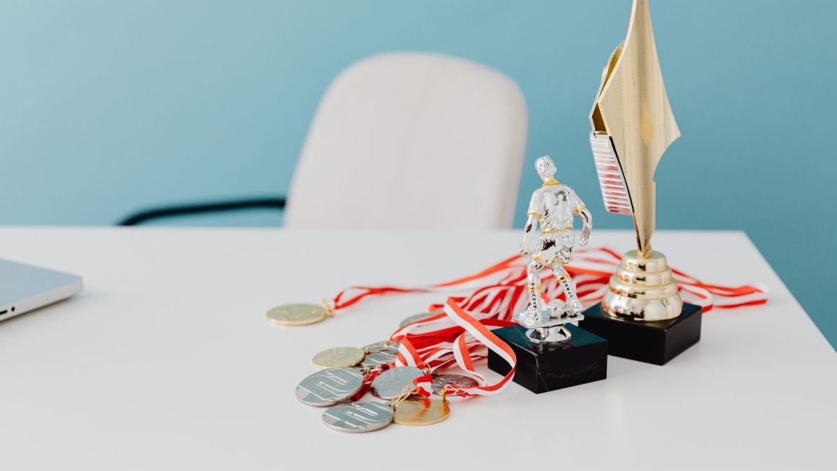 A collection of trophies and medals displayed on a white desk, symbolizing success and victory.