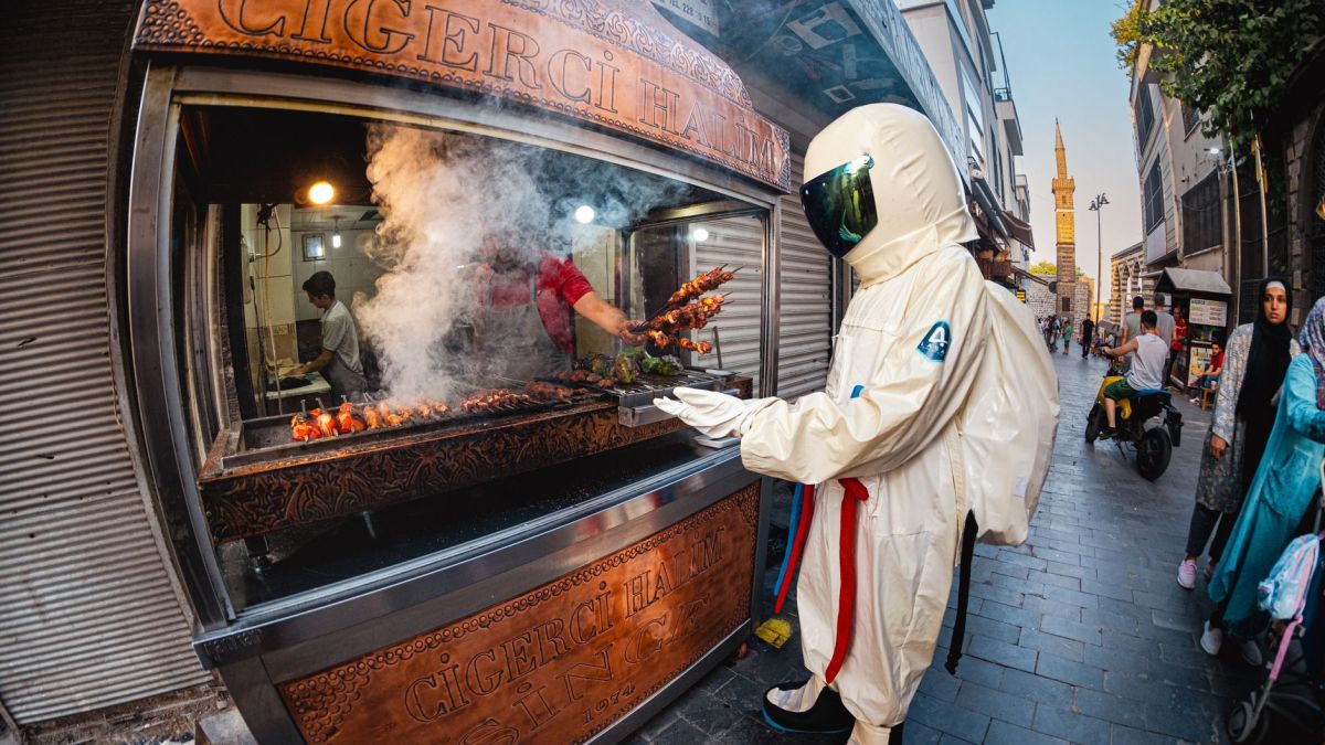 Astronaut costume in Diyarbakır street enjoying Turkish kebabs. Unique dining experience.