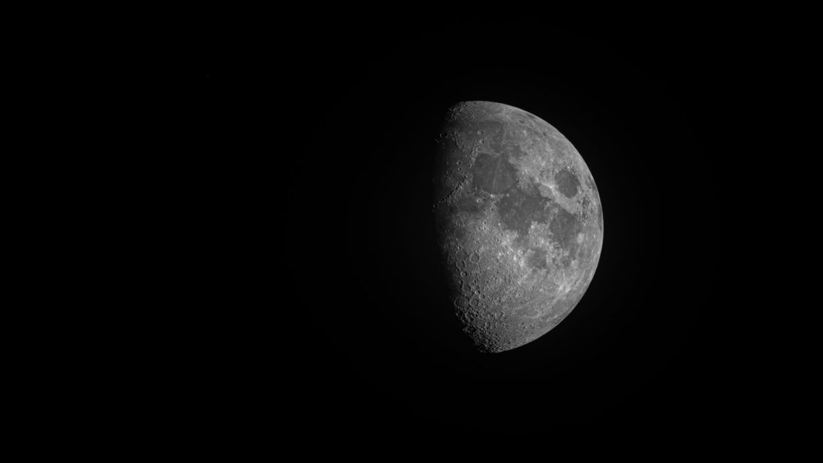 High-contrast black and white photo of a half moon in the night sky.