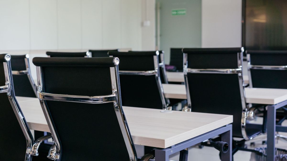 Sleek modern conference room with black chairs and white desks, suitable for business meetings.