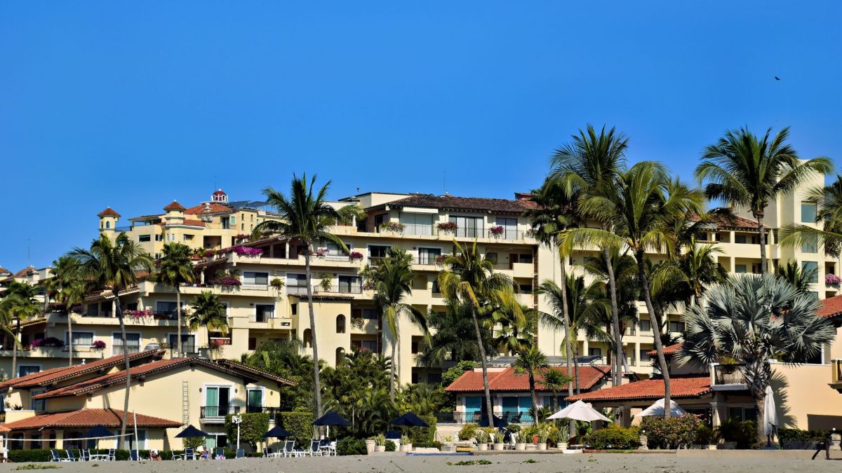 Tropical resort in Puerto Vallarta, Mexico, surrounded by palm trees and blue skies.