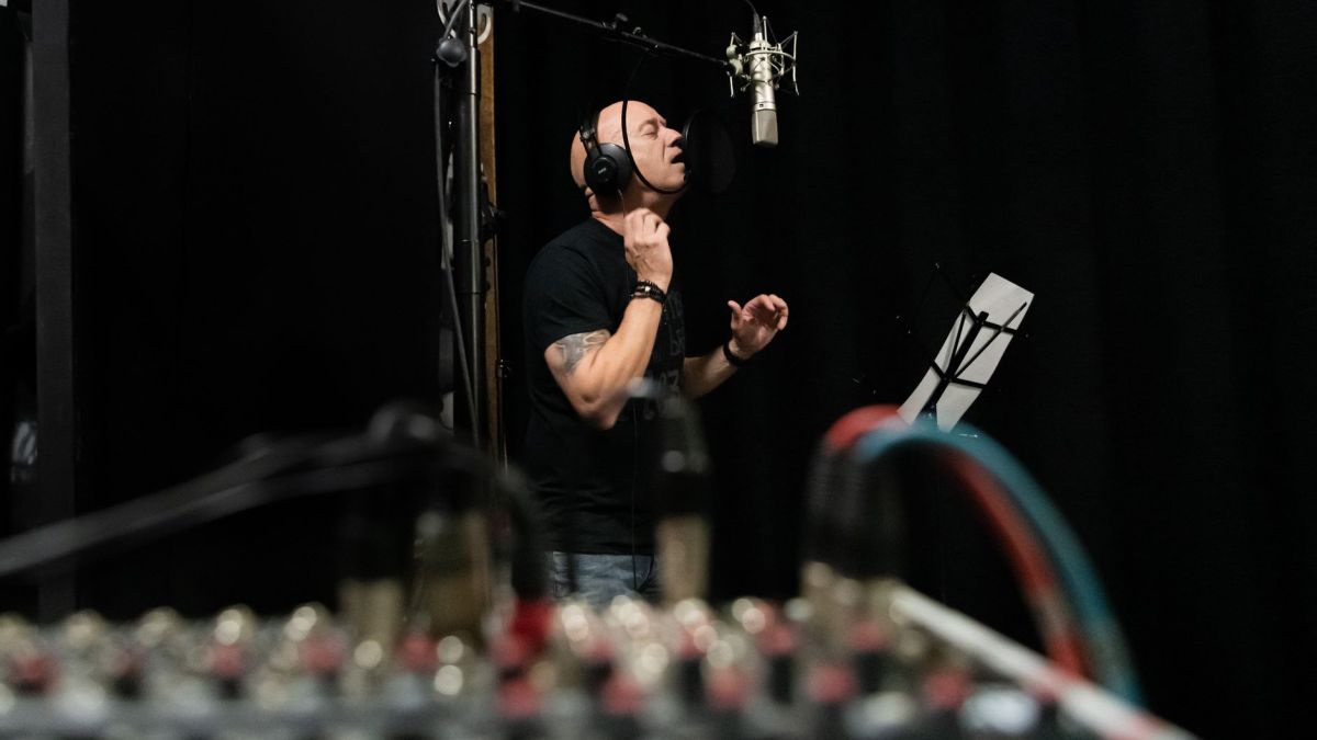 A vocalist intensely performing in a professional recording studio setting.