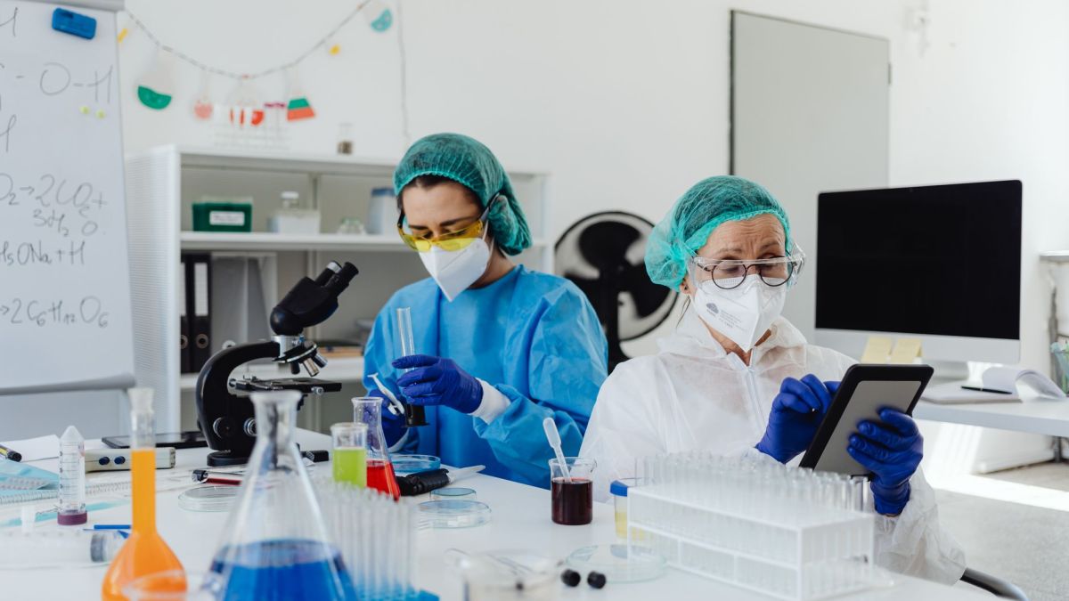 Researchers conducting experiments in a laboratory, using microscopes and digital tablets.
