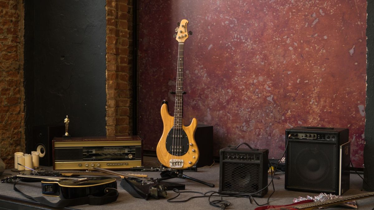 S type electric guitar placed on stage near various musical instruments and loudspeakers in shabby studio