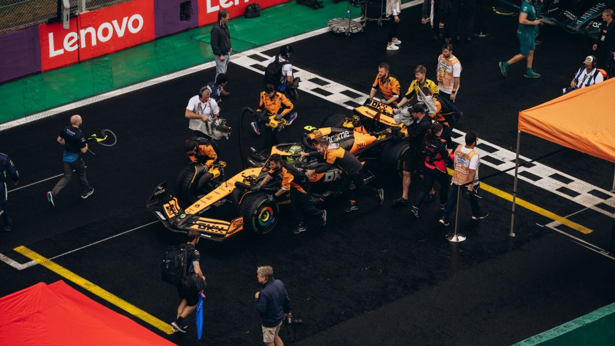 A Formula 1 pit crew preparing a car for the race on a rainy day, teamwork in action.