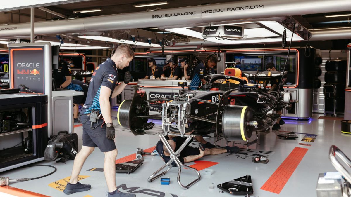 Mechanics working on a Formula One racing car in a professional garage setup.