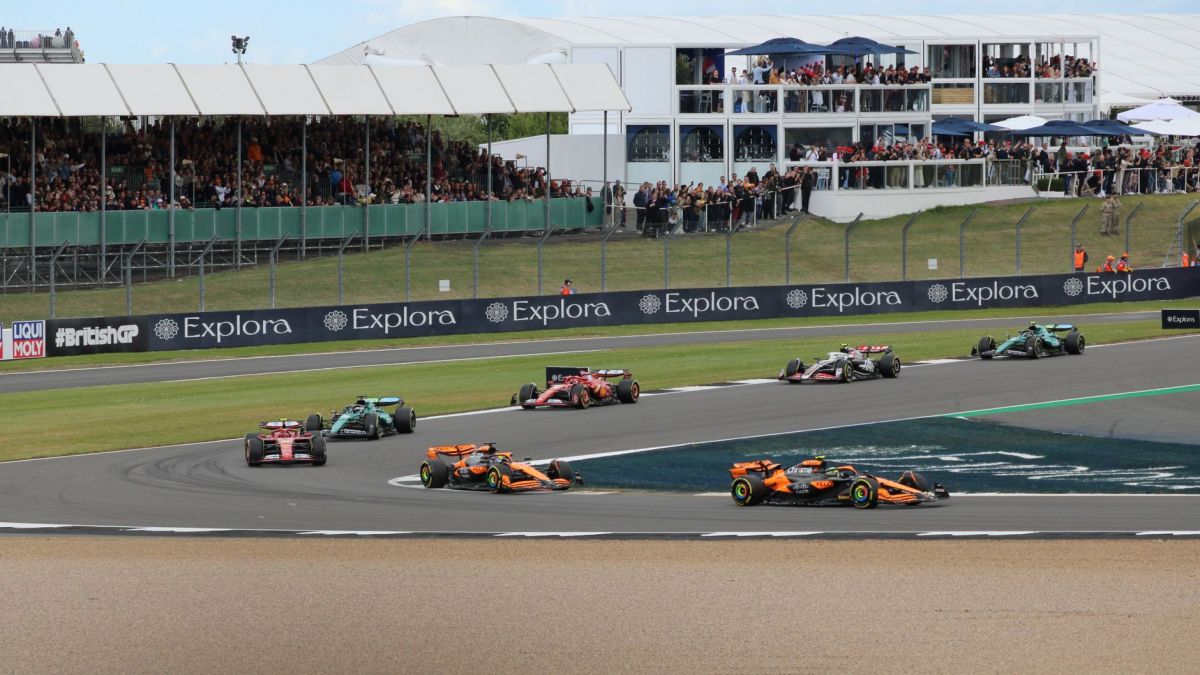 Thrilling car race at Silverstone Circuit with packed grandstands and vibrant crowd.