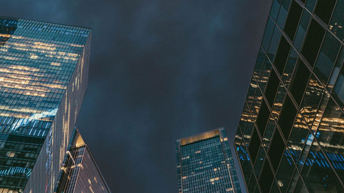 Low-angle shot of illuminated skyscrapers reflecting lights against a dark evening sky in Moscow.