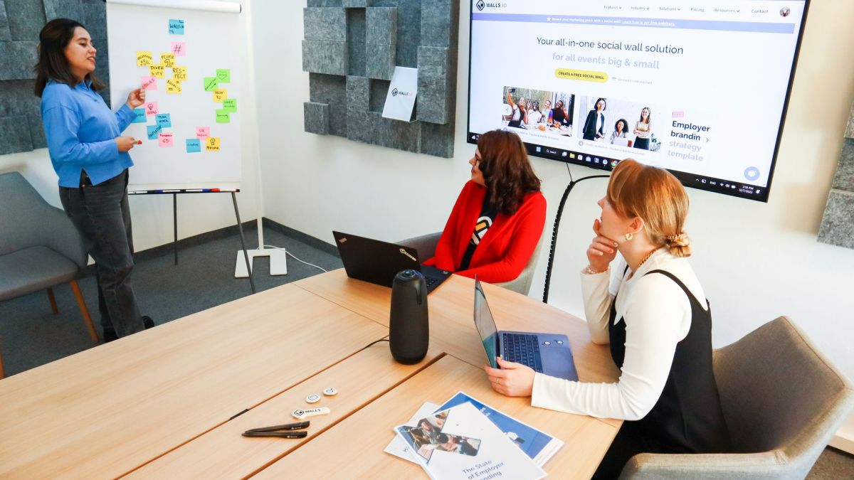 Three women collaborate in a conference room using digital tools for effective teamwork.
