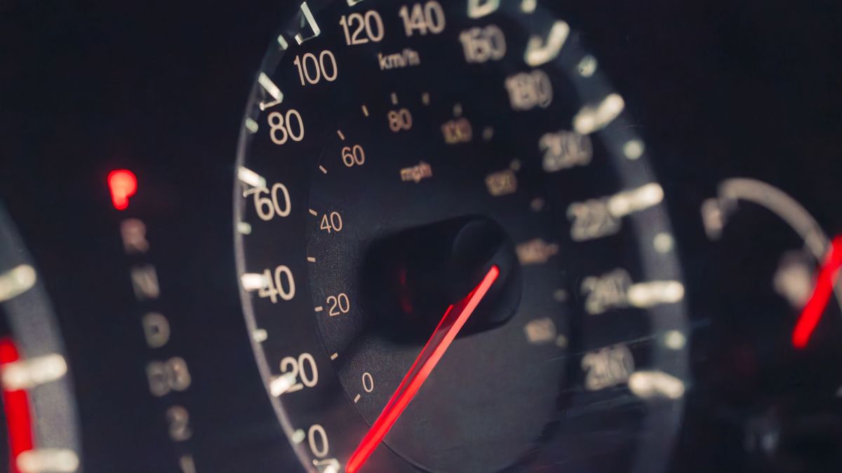 Detailed view of a car speedometer showing km/h and mph in low light settings.