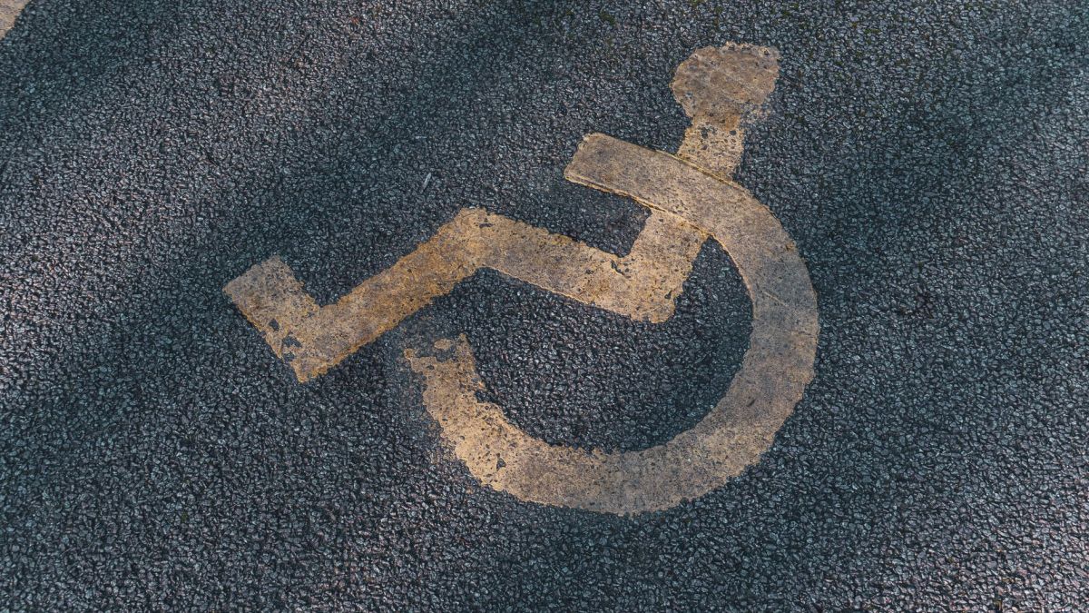 A close-up of a wheelchair symbol on asphalt, representing accessibility.